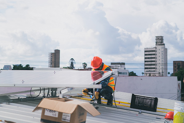 Imagen de un trabajador instalando un panel solar en un edificio