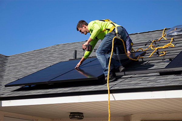Imagen de una persona instalando una placa solar en un chalet